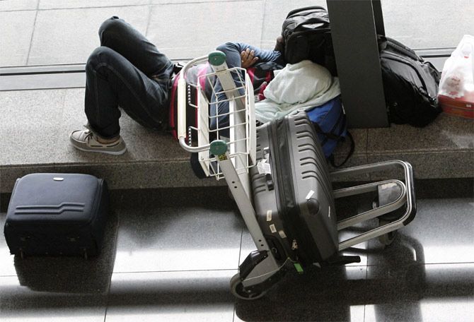 A stranded passenger sleeps at the lobby of Ninoy Aquino International airport in Pasay city, after nearly 200 local flights were suspended due to Typhoon Haiyan on Friday
