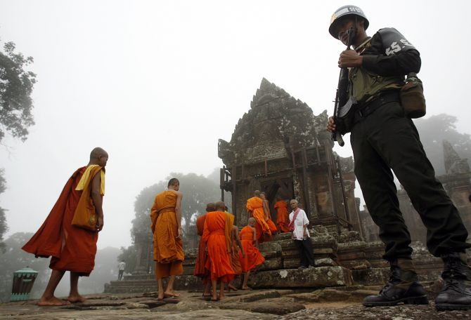 Monks walk past a Combodian soldier to attend a Buddhism ceremony praying for peace called Krong Pealy at Preah Vihear temple 