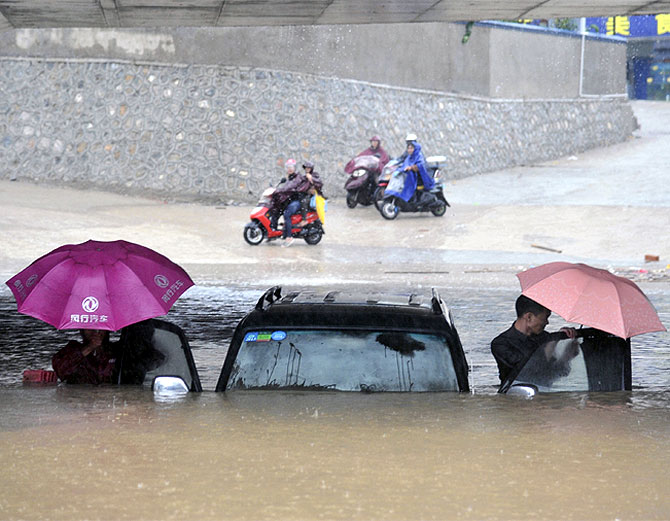 People get out of a stranded car at a flooded underpass amid heavy rainfalls under the influence of Typhoon Haiyan, in Nanning, Guangxi Zhuang Autonomous Region