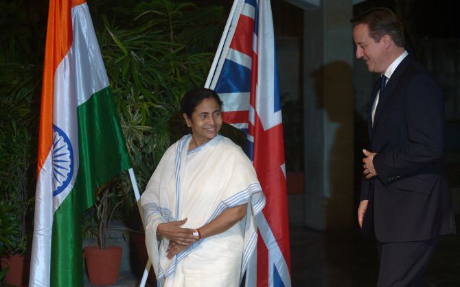 Britain's Prime Minister David Cameron walks with the Chief Minister of West Bengal Mamata Banerjee at the British Deputy High Commission in Kolkata