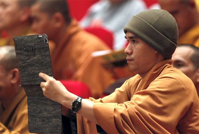 A monk films, with an iPad, a ceremony in Hanoi, Vietnam