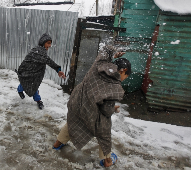 Kashmiri boys play in snow as temperatures drop in the Valley