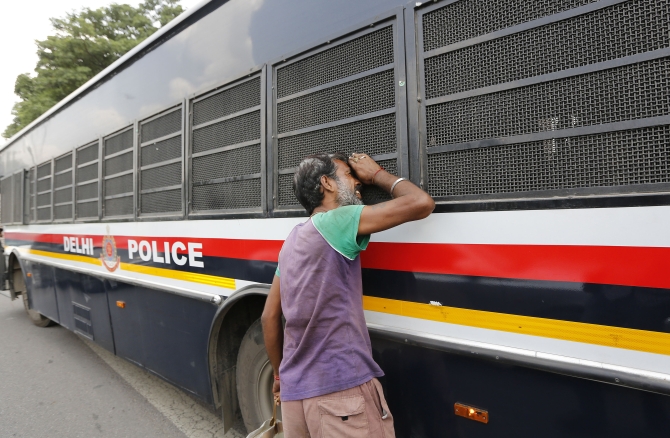 A man peeks into the police vehicle carrying four men who were sentenced to death for the fatal gang-rape