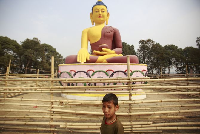 A child plays in front of a giant idol of Lord Buddha in Lalitpur