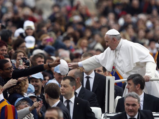 A faithful gives a hat to exchange with Pope Francis as he arrives to conduct his weekly general audience at St. Peter's Square at the Vatican 