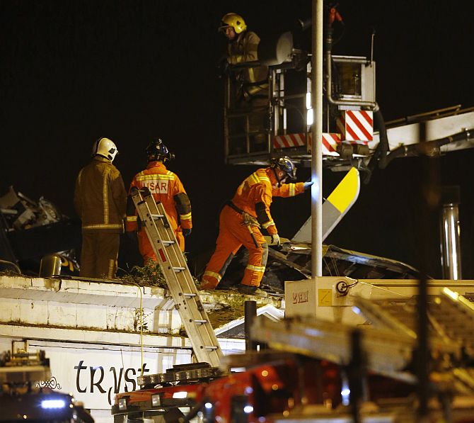 Rescue workers examine the wreckage of a police helicopter which crashed onto the roof of the Clutha Vaults pub in Glasgow, Scotland