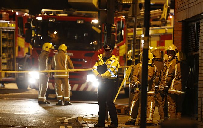 Rescue workers gather near the scene where a police helicopter crashed onto the roof of the Clutha Vaults pub in Glasgow