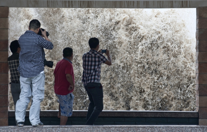 People take pictures of a storm surge under the influence of Typhoon Fitow in Wenling