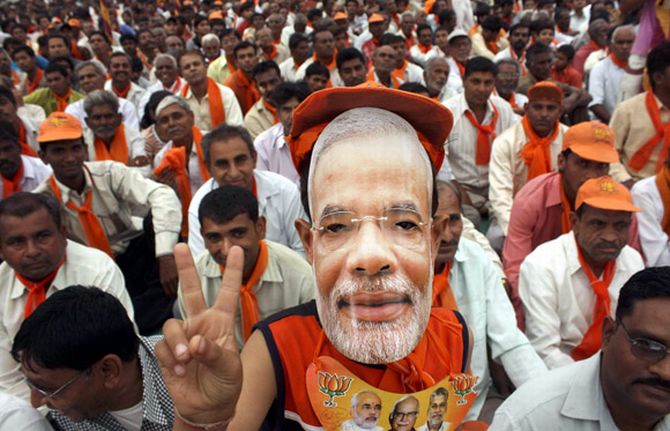A supporter wears a mask of Narendra Modi during a rally in Gujarat