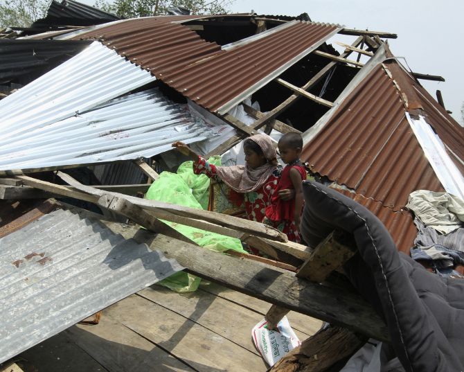 A woman tries to retrieve her belongings after her house was destroyed by cyclone Mahasen, in Kuakata, Bangaladesh in May, 2013. 