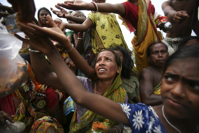 Villagers, displaced from their homes by a tidal wave caused by cyclone Aila, wait for food being distributed by members of an NGO in Sundarbans, West Bengal, in June, 2009. 
