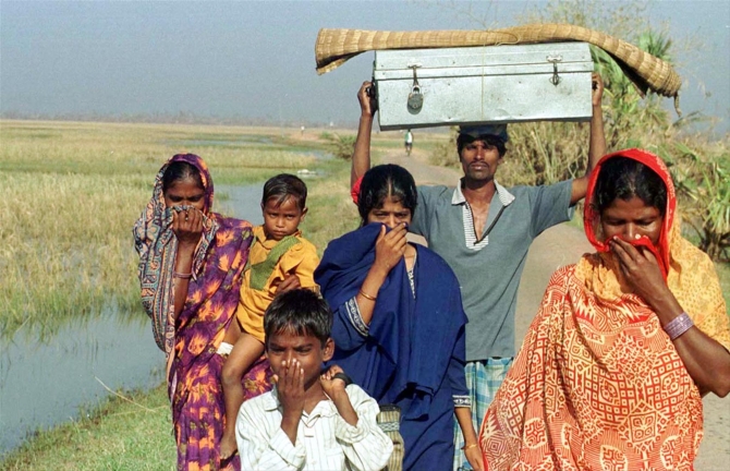 Residents cover their noses to avoid the stench from the badly decomposed bodies and carcasses on the way to safe place in Ersama village after the 1999 cyclone