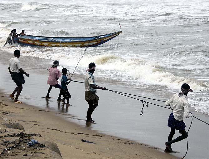 Fishermen pull a boat from the waters of the Bay of Bengal to safer ground at Podampata village in Ganjam district in the eastern Indian state of Odisha