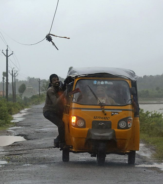 A man tries to avoid a broken electricity cable as he rides on an auto rickshaw in Ichapuram town in Srikakulam district of Andhra Pradesh