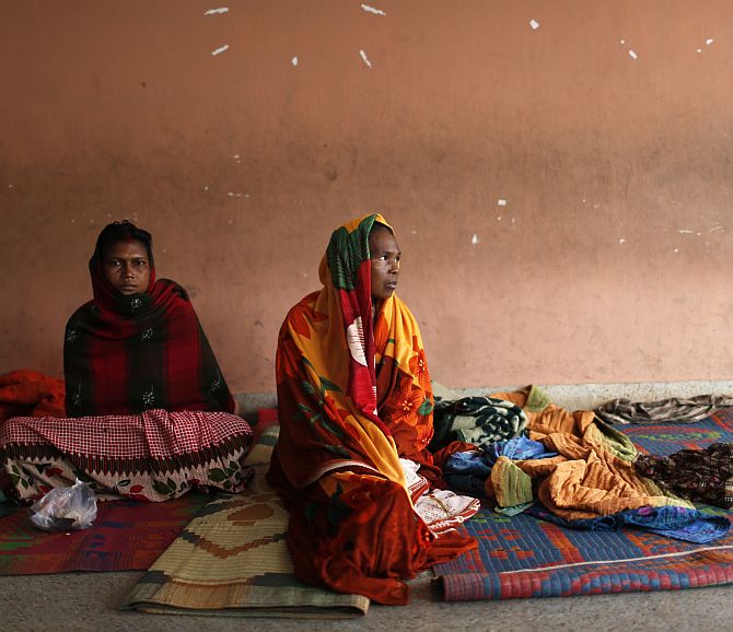 Women sit in a school compound after leaving their houses to take shelter from the impact of Cyclone Phailin
