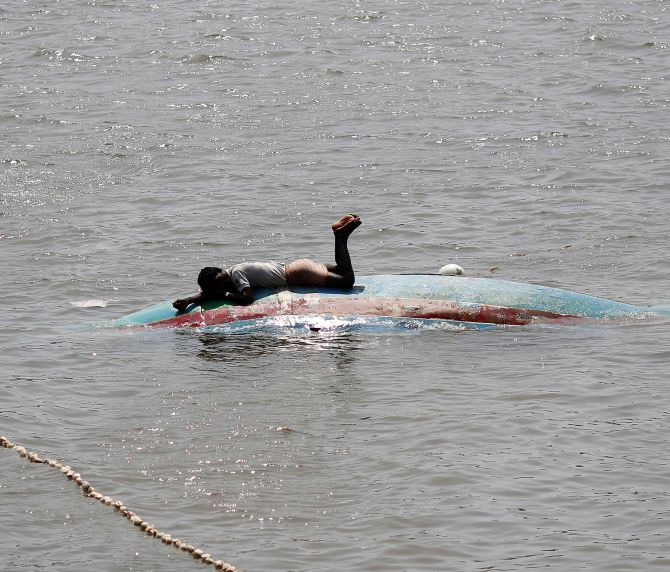 A fisherman lies on his overturned boat on Monday after Cyclone Phailin hit Gopalpur port in Odisha