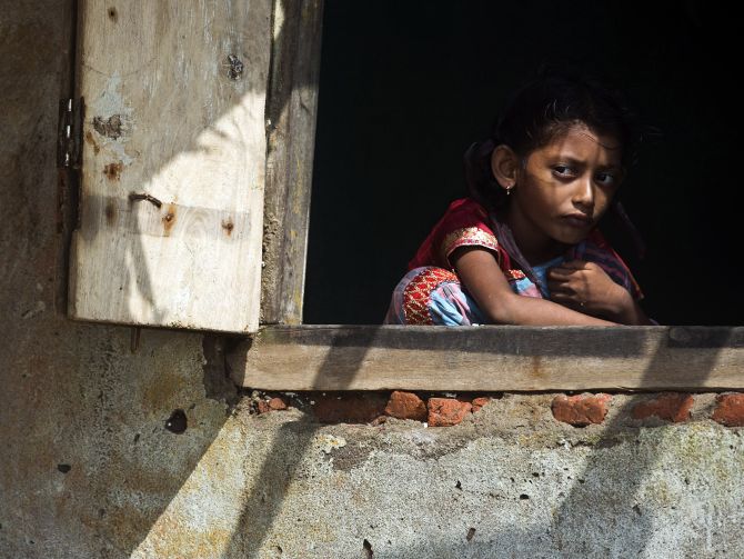 A girl looks out from the window of her partially damaged house on Monday after Cyclone Phailin hit Puri