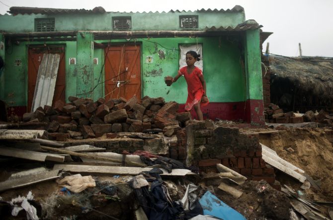 A girl removes debris from her damaged house on Monday after Cyclone Phailin hit Puri in Odisha