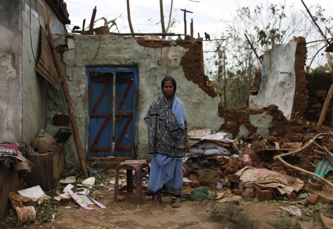 A woman stands outside her damaged house after Cyclone Phailin hit Gopalpur in Ganjam district in Odisha