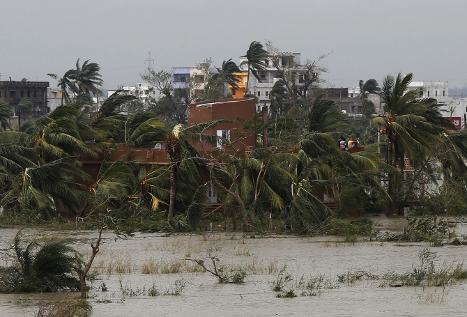 People sit on the roof of a house after Cyclone Phailin hit Brahmapur town in Ganjam district in Odisha