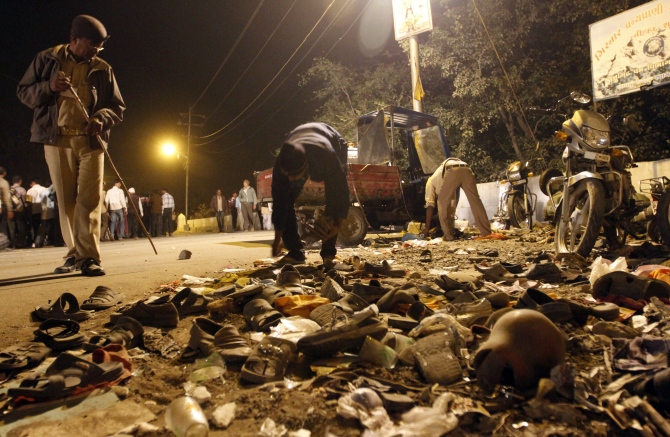 A man collects shoes left behind during a stampede last year in Junagadh district in Gujarat