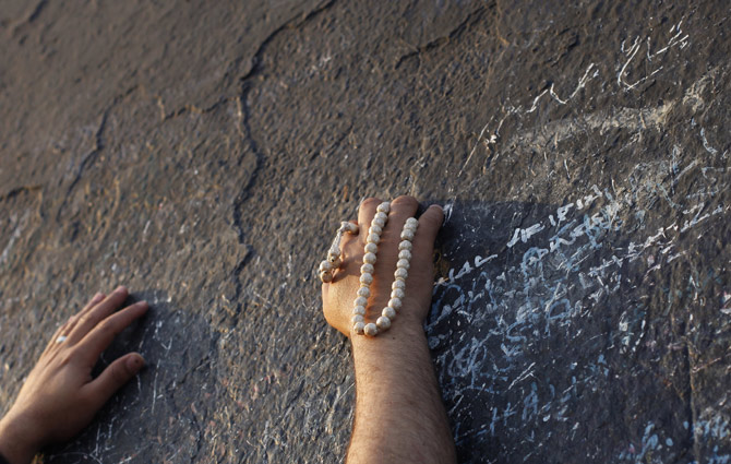 A Muslim pilgrim touches the rocks atop Mount Mercy on the plains of Arafat during the peak of the annual haj pilgrimage