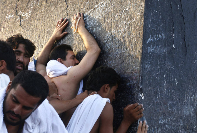 Muslim pilgrims touch the rocks atop Mount Mercy on the plains of Arafat during the peak of the annual haj pilgrimage