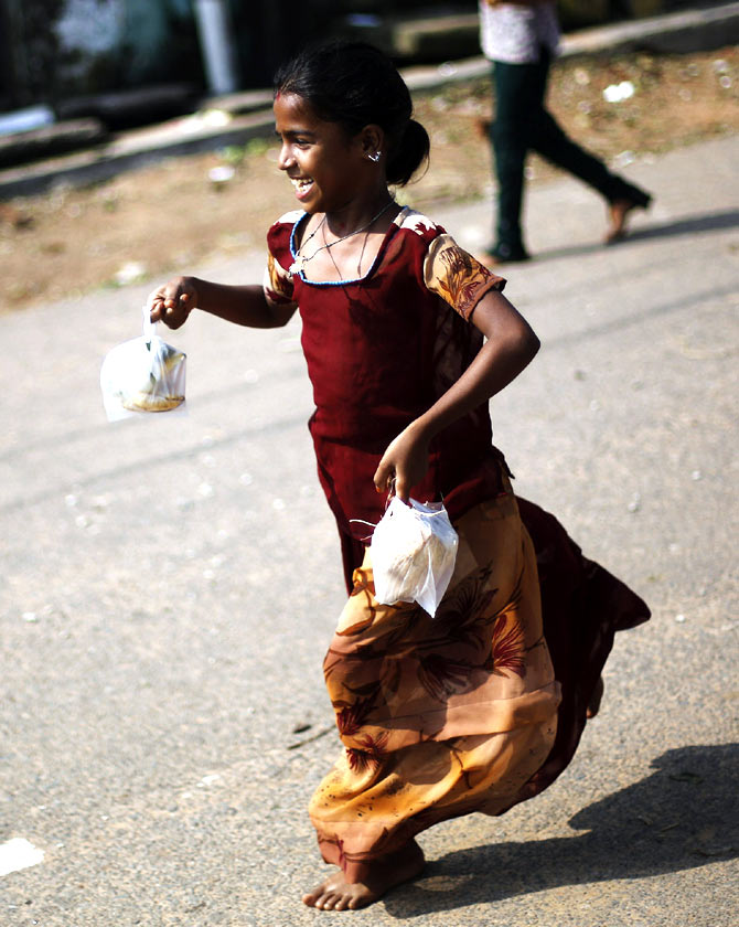 A girl runs home after receiving a free meal for breakfast at the cyclone-hit Gopalpur village, in Ganjam district in the eastern Indian state of Odisha