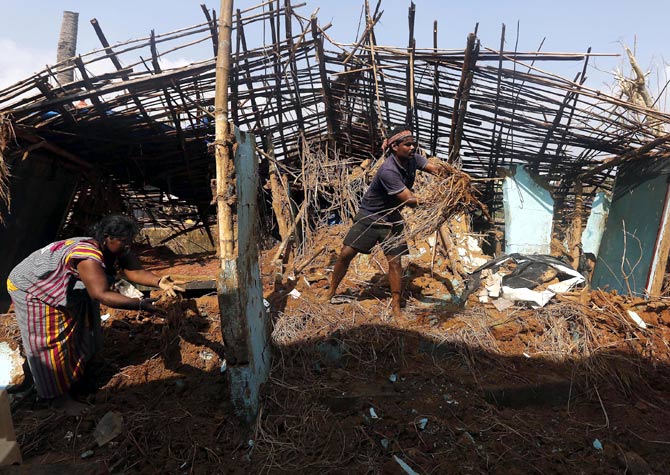 A fisherman and his wife clear the debris from their damaged house in Gopalpur