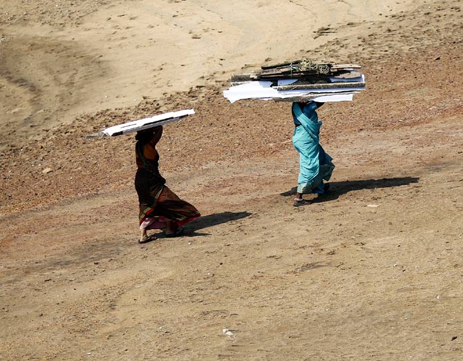 Women carry pieces of a temporary roof to rebuild their houses after Cyclone Phailin hit Arjyapalli village, in Ganjam district