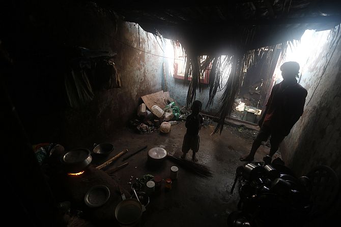 A man and his son stand inside their damaged house after Cyclone Phailin hit Gopalpur village in Ganjam district