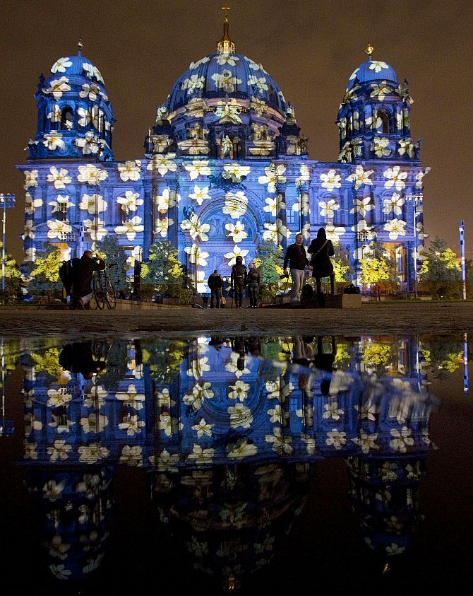 People look at a light installation at the Berlin Cathedral during the opening day of the Festival of Light show in Berlin