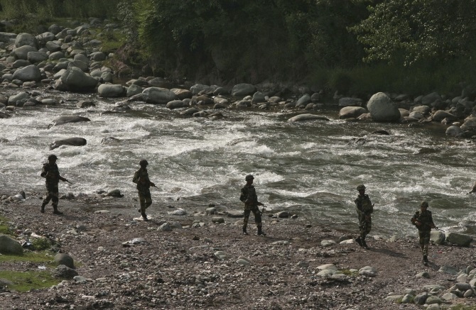 Border Security Force soldiers patrol next to a stream near the Line of Control in Poonch