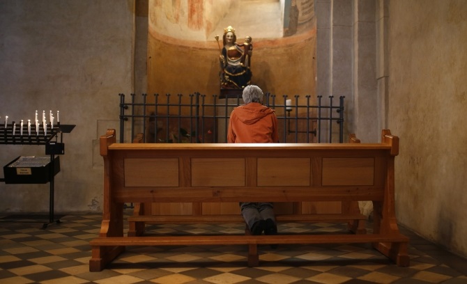 A woman kneels in prayer inside Limburg cathedral