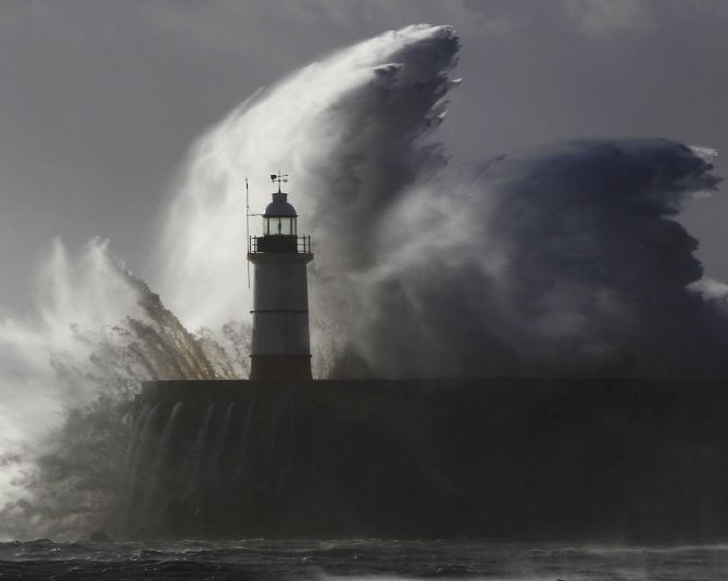 Huge waves crash against a lighthouse as storm 'St Jude' batters Newhaven in South England on Monday