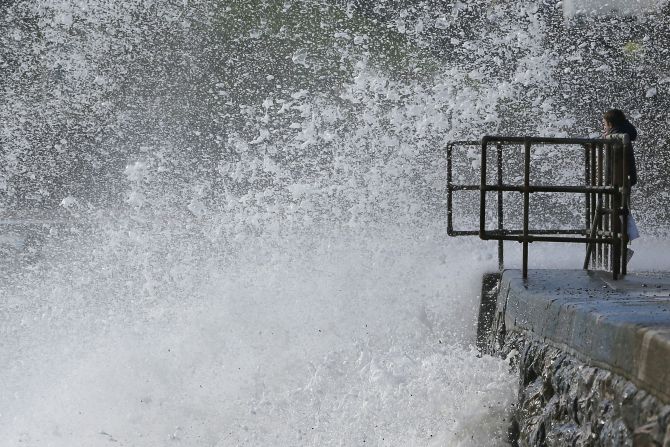 A young boy watches as waves crash against the seafront at Dawlish in Devon, on Monday.