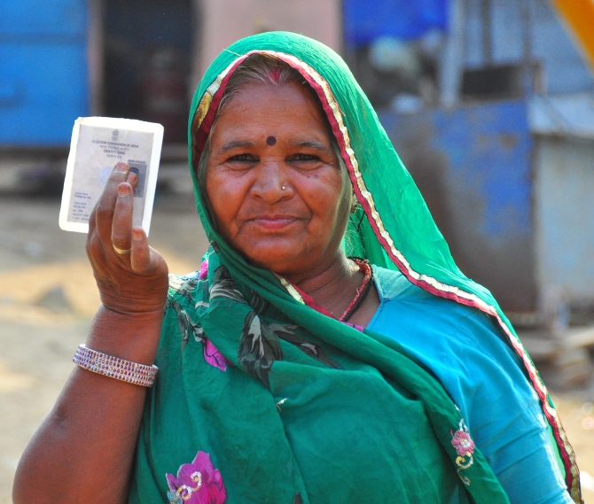 A woman voter shows her voter identity card