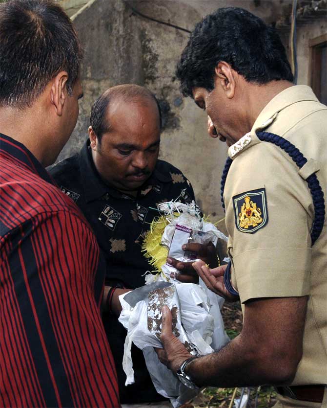 Policemen inspect a substance found at the site of a bomb blast in Bangalore