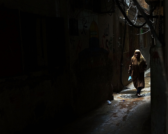 A woman walks down an alley in a poor neighborhood with a high concentration of Syrian refugees in Beirut, Lebanon