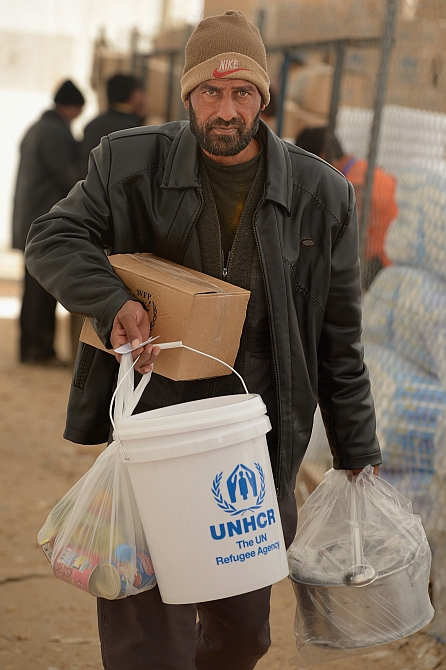 A refugee from Syria collects food and supplies from the UNHCR as he arrives at the Za'atari refugee camp in Mafrq, Jordan