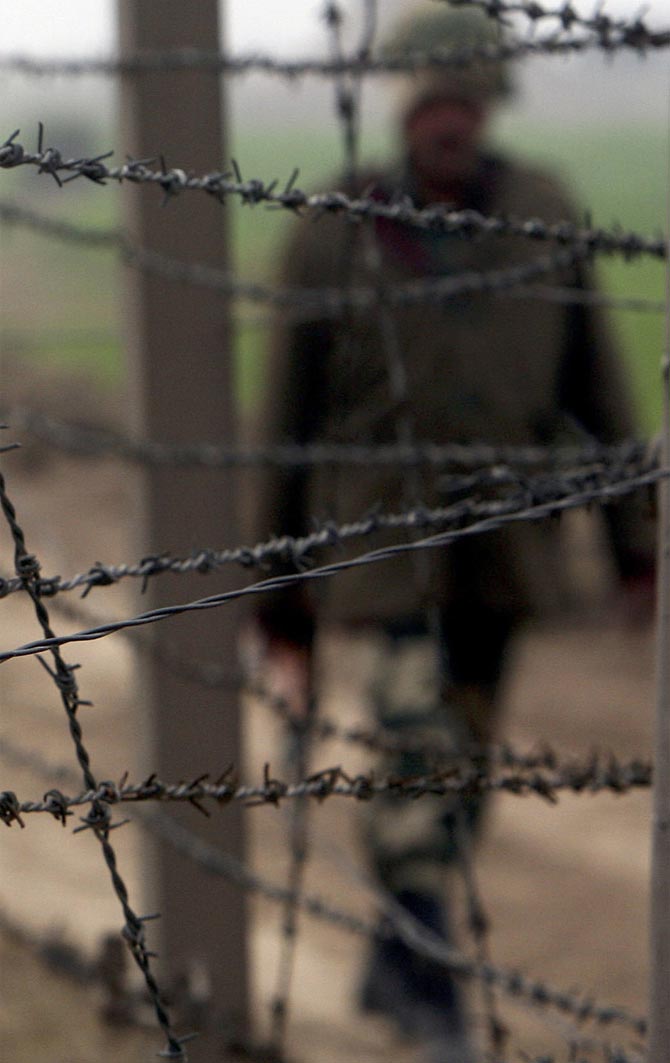 A BSF soldier patrols near the fenced border with Pakistan in Suchetgarh, southwest of Jammu
