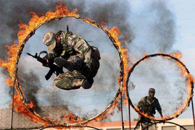 A soldier from the People's Liberation Army jumps through a ring of fire as part of training during the PLA Army Day in Wenzhou, Zhejiang province