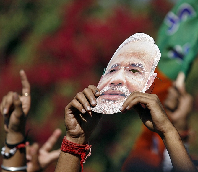A BJP supporter holds a mask during a rally