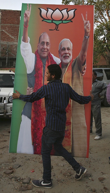 An activist of the Bharatiya Janata Party carries a hoarding featuring Gujarat Chief Minister Narendra Modi and Rajnath Singh, president of the BJP, during celebrations before Modi was crowned as the prime ministerial candidate for the party, in Jammu