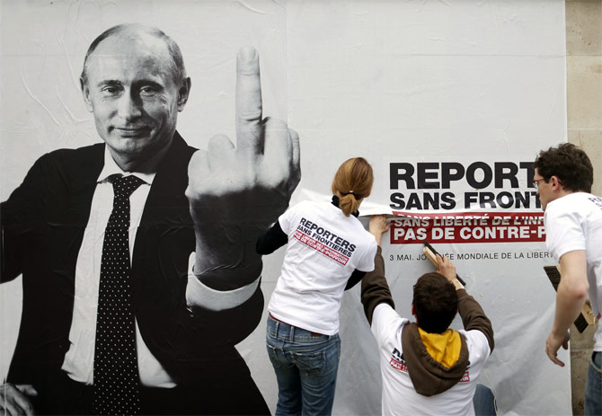 Activists from Reporters Without Borders paste a poster depicting Russia's President Vladimir Putin to mark the 20th annual World Press Freedom day