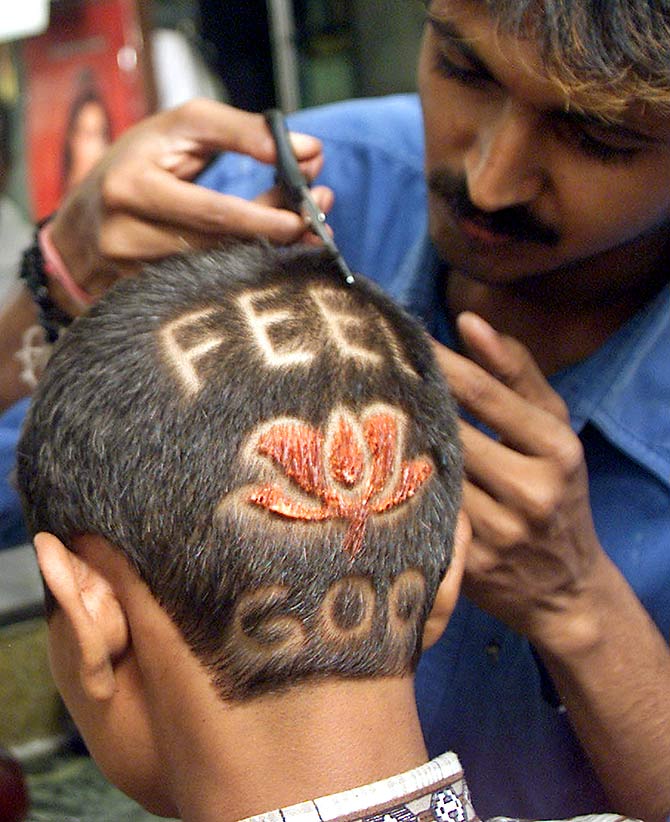 A barber applies finishing touches to a lotus hairstyle he designed for a supporter of the BJP