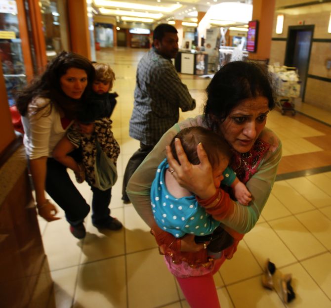 Women carrying children run for safety as armed police hunt gunmen who went on a shooting spree in Westgate shopping centre in Nairobi on Saturday. 