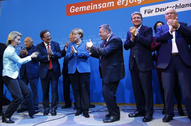 German Chancellor and leader of the Christian Democratic Union Angela Merkel (C) and CDU party fellows sing as they celebrate after first exit polls in the German general election at the CDU party headquarters in Berlin
