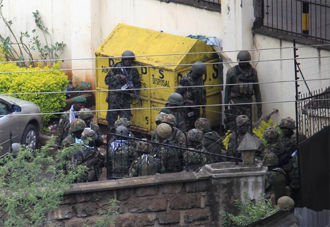 Kenya defence forces soldiers take cover behind a wall