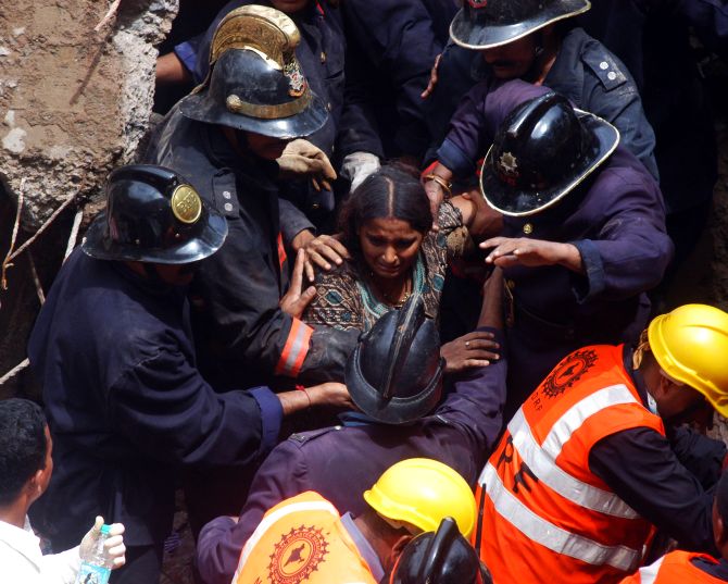 Firefighters rescue a trapped woman at the building collapse site in Mumbai